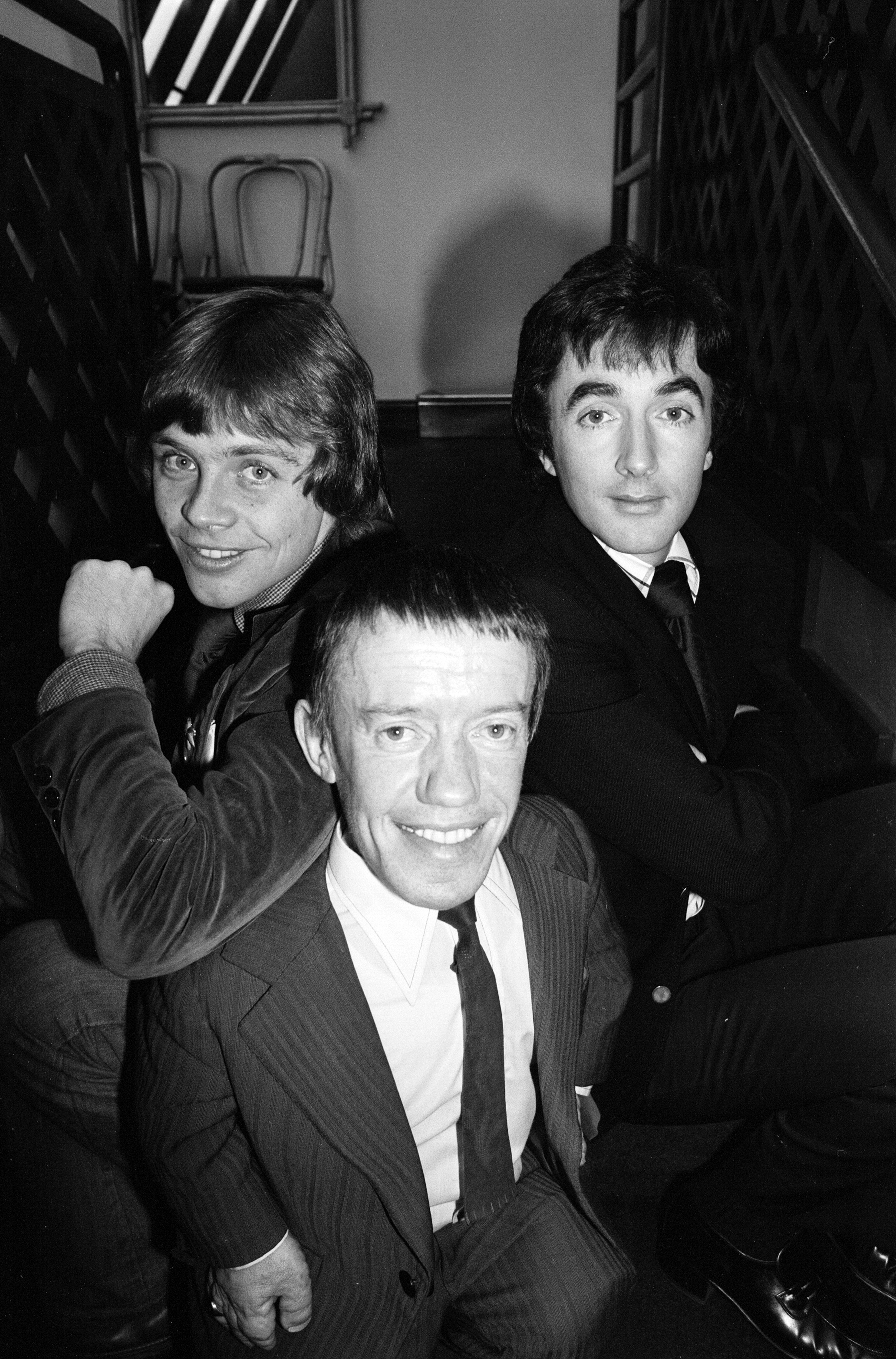 Three men successful  suits airs  connected  a staircase, smiling astatine  the camera