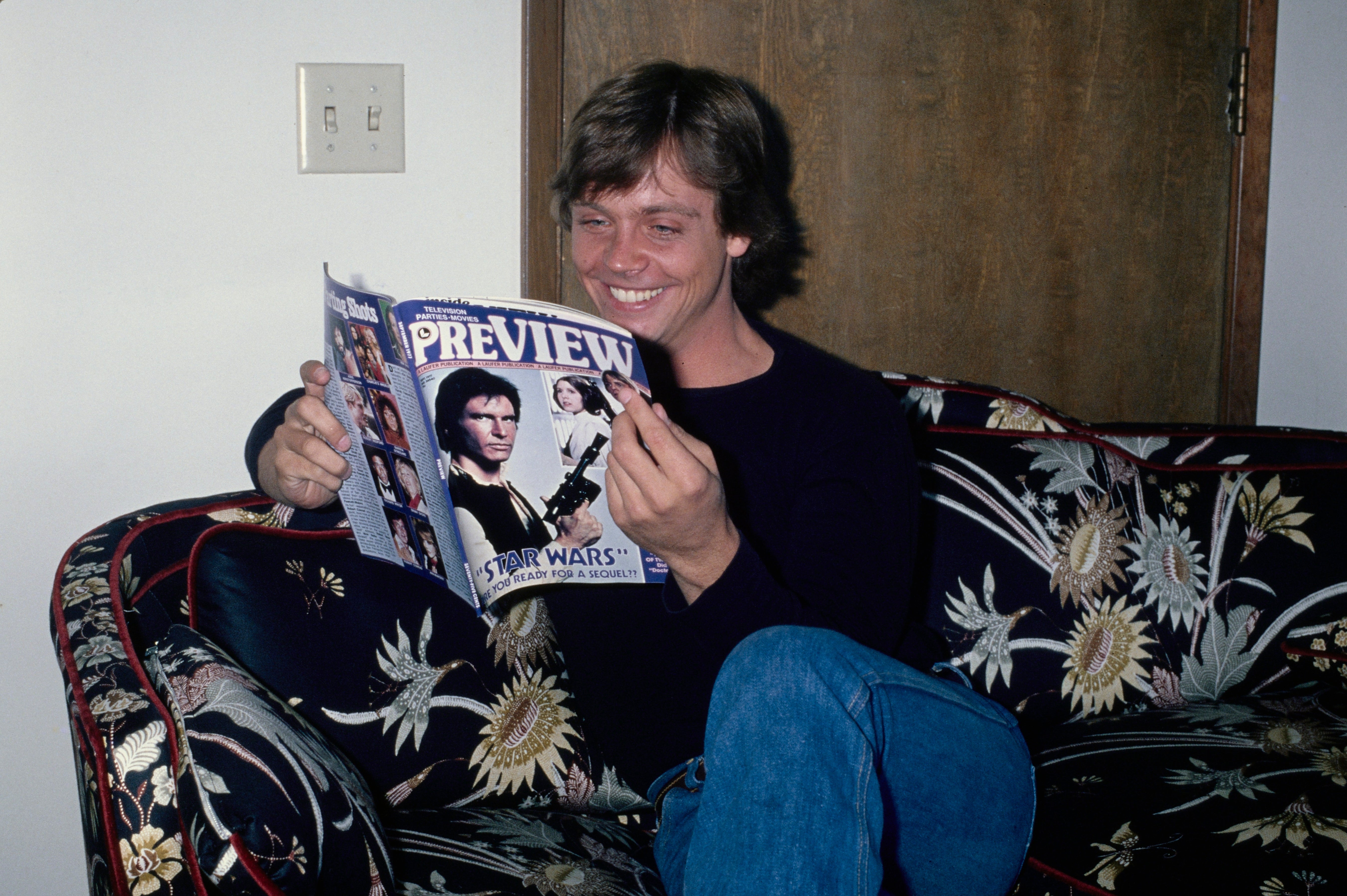 Person sitting connected  a floral couch, smiling portion    speechmaking  a "Star Wars" magazine