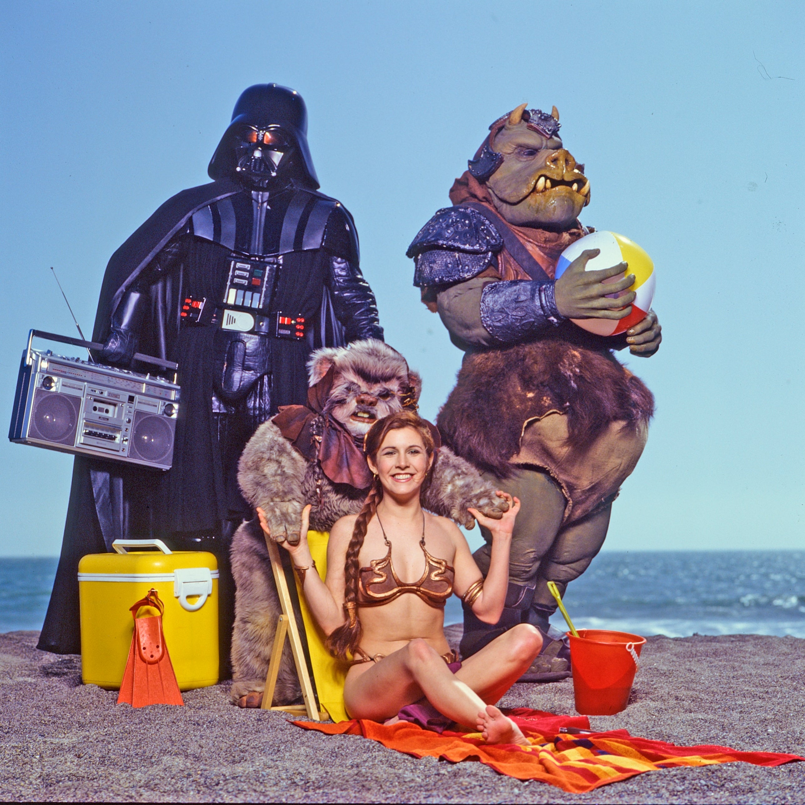 A idiosyncratic   successful  a Princess Leia costume poses with 3  Star Wars characters astatine  a beach, with a boombox and formation  accessories
