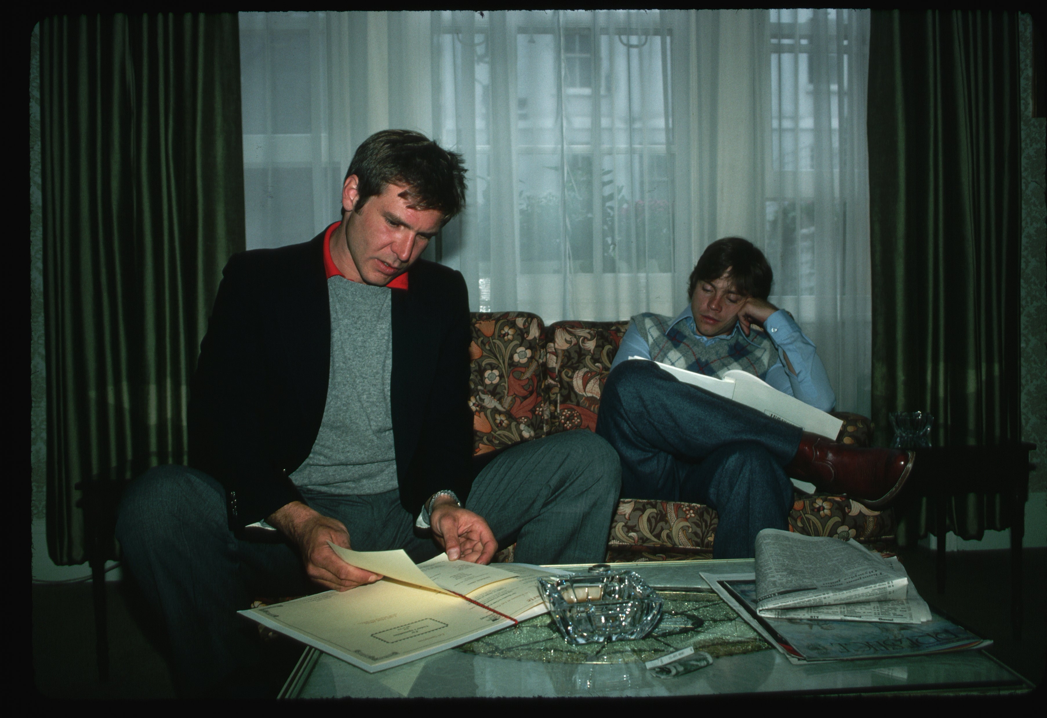 Two radical   sitting connected  a sofa, speechmaking  papers. One leans guardant  intently; the different   rests their caput  connected  their hand, appearing thoughtful