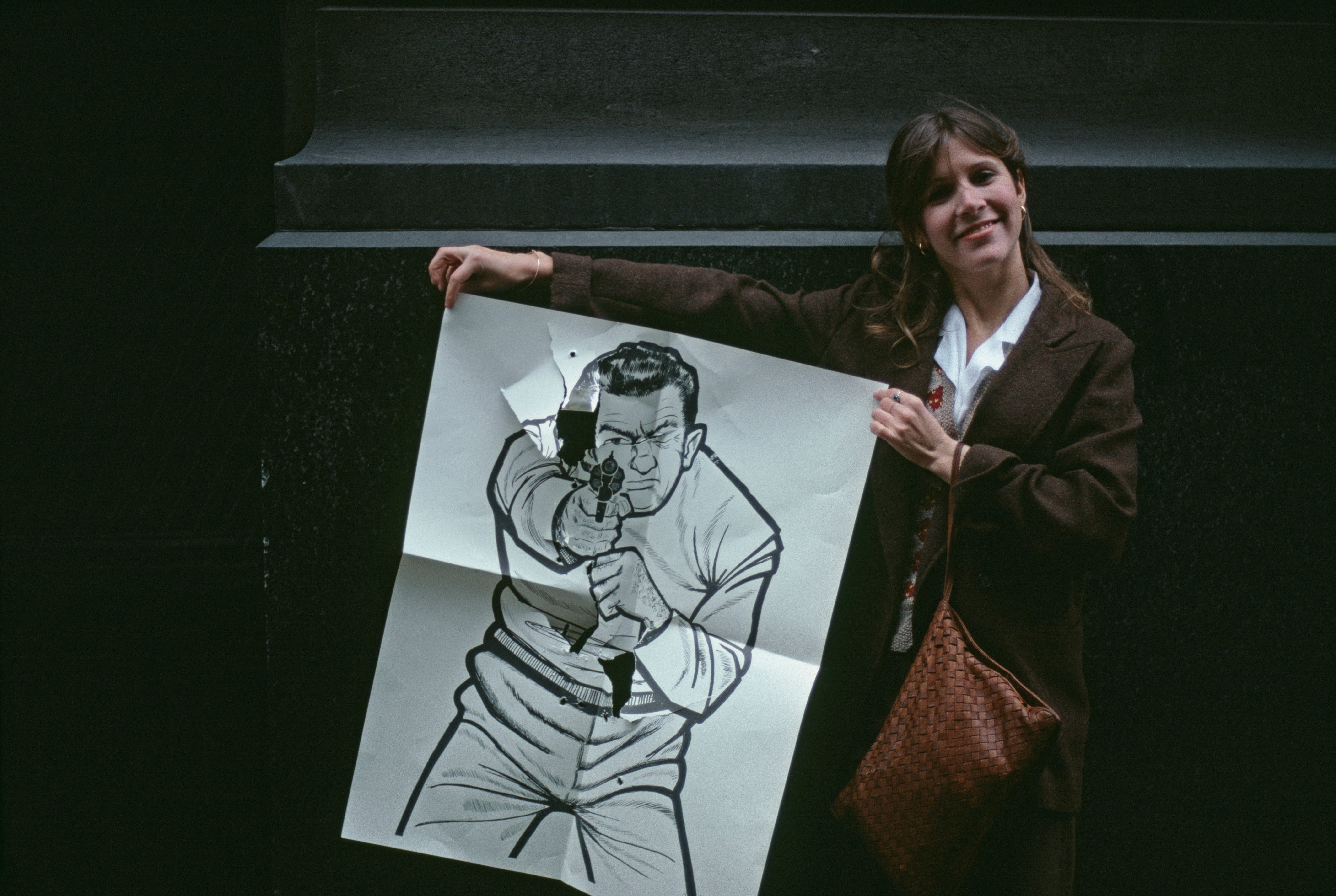 A pistillate   successful  a suit   smiles, holding a ample  insubstantial  people     with a cartoon fig  aiming a gun