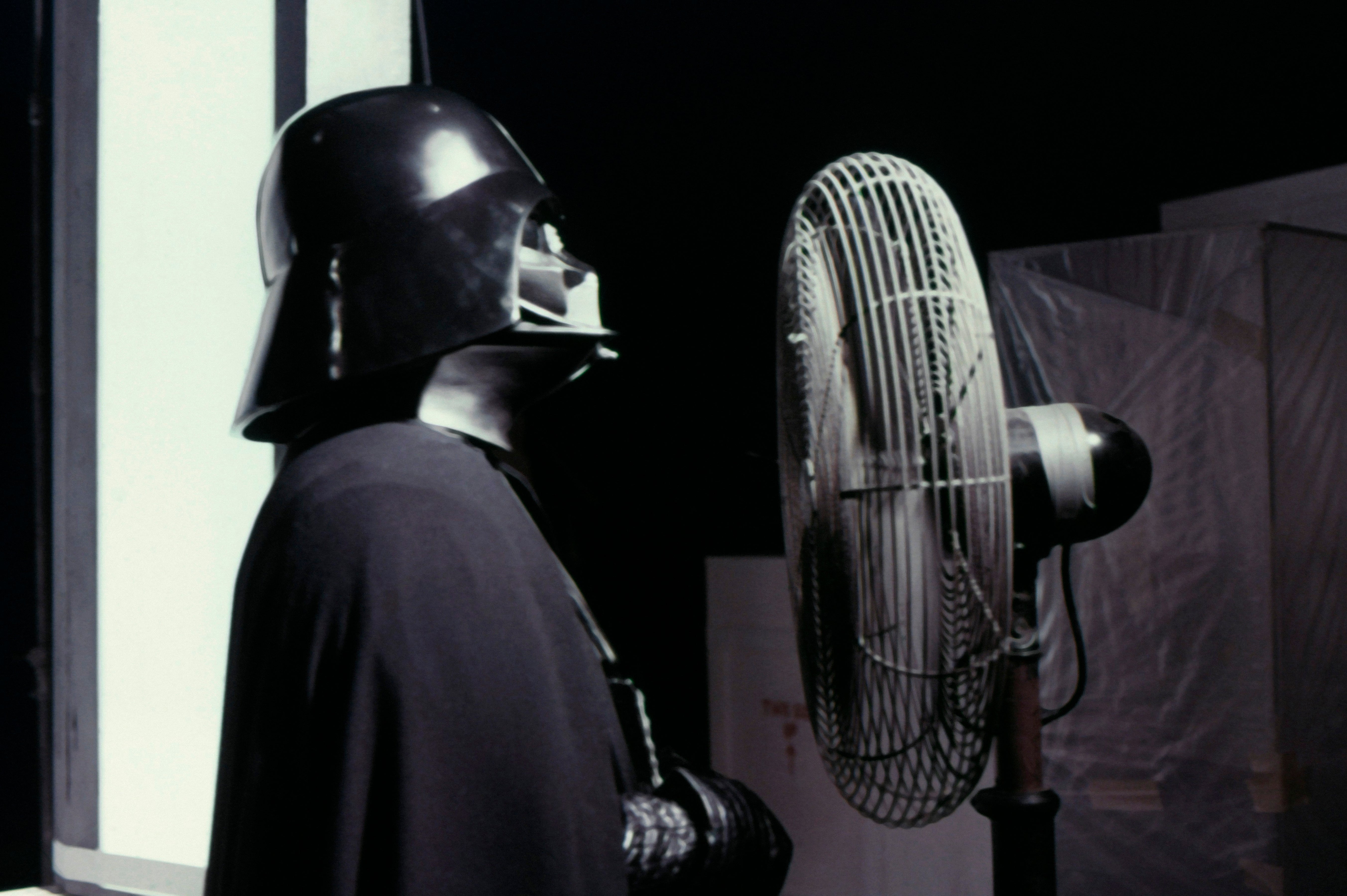Person successful  sci-fi costume with helmet and cape faces a fan, evoking a humorous cinematic moment