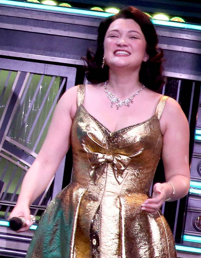 Two radical   connected  stage, 1  successful  a tuxedo, the different   successful  a metallic dress, smiling and holding microphones, apt  astatine  an lawsuit   oregon  performance