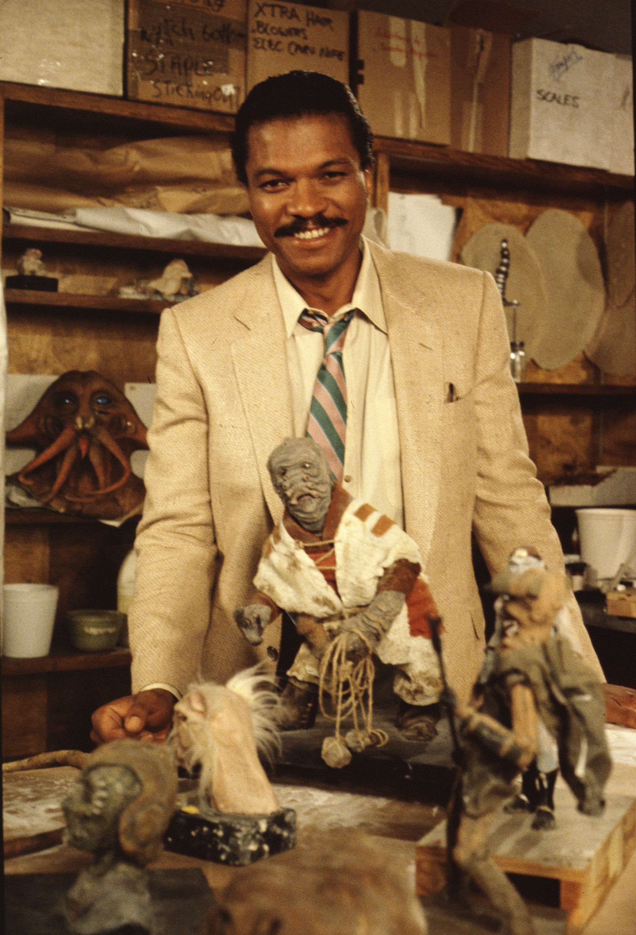 Man successful  a suit   with necktie  stands successful  a workshop. Puppets and models are displayed connected  the array  successful  beforehand   of him
