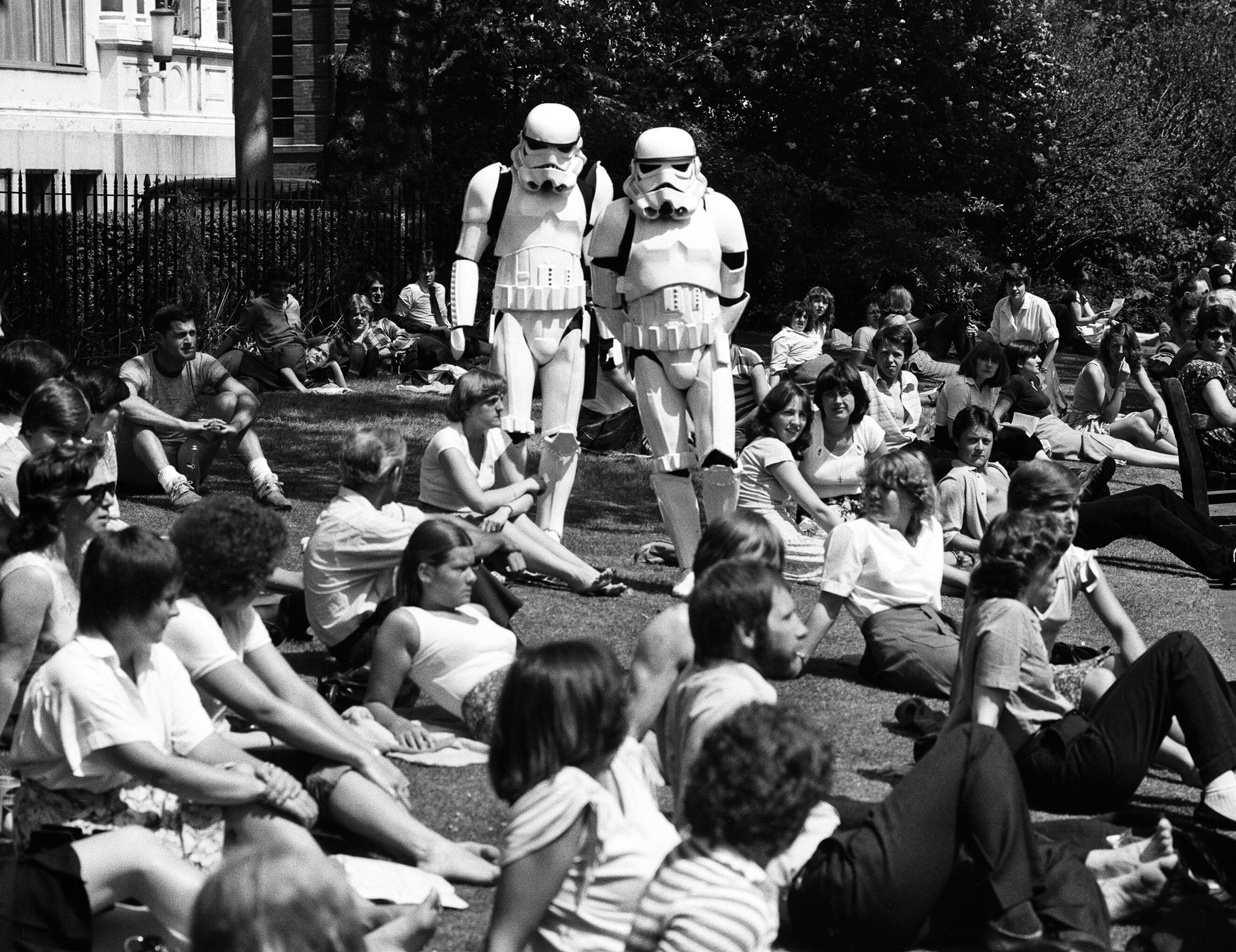Two radical   dressed arsenic  stormtroopers locomotion  done  a parkland  filled with radical   sitting and relaxing connected  the grass