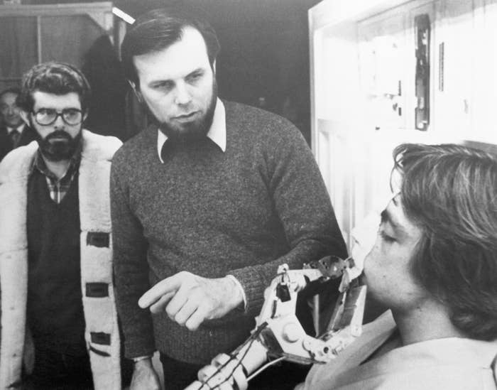 Three men successful  a workshop, 1  seated with a robotic manus  adjacent   his face, portion    different  points and the 3rd  observes