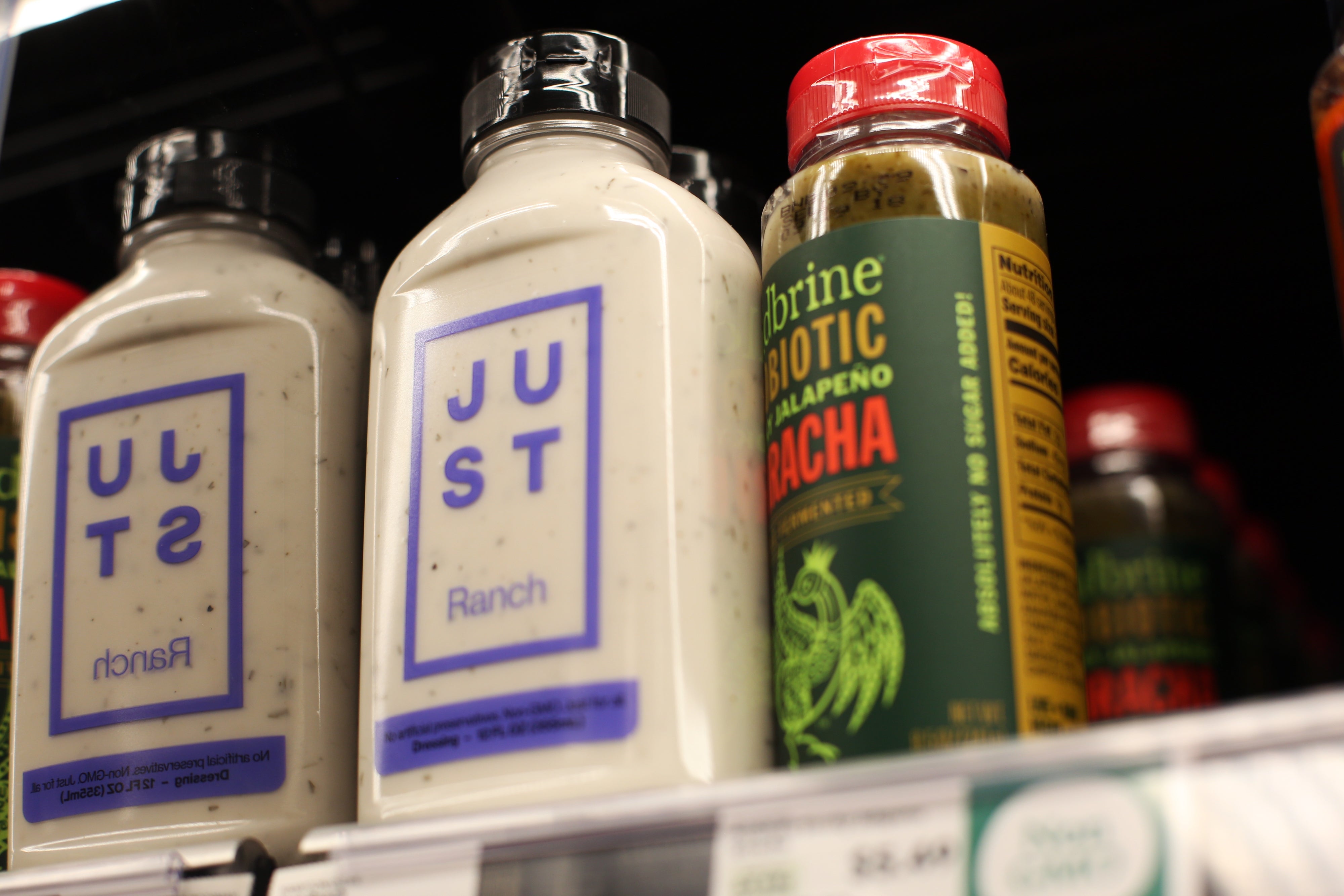 Bottles of ranch dressing and jalapeño sriracha blistery condiment connected a market store shelf