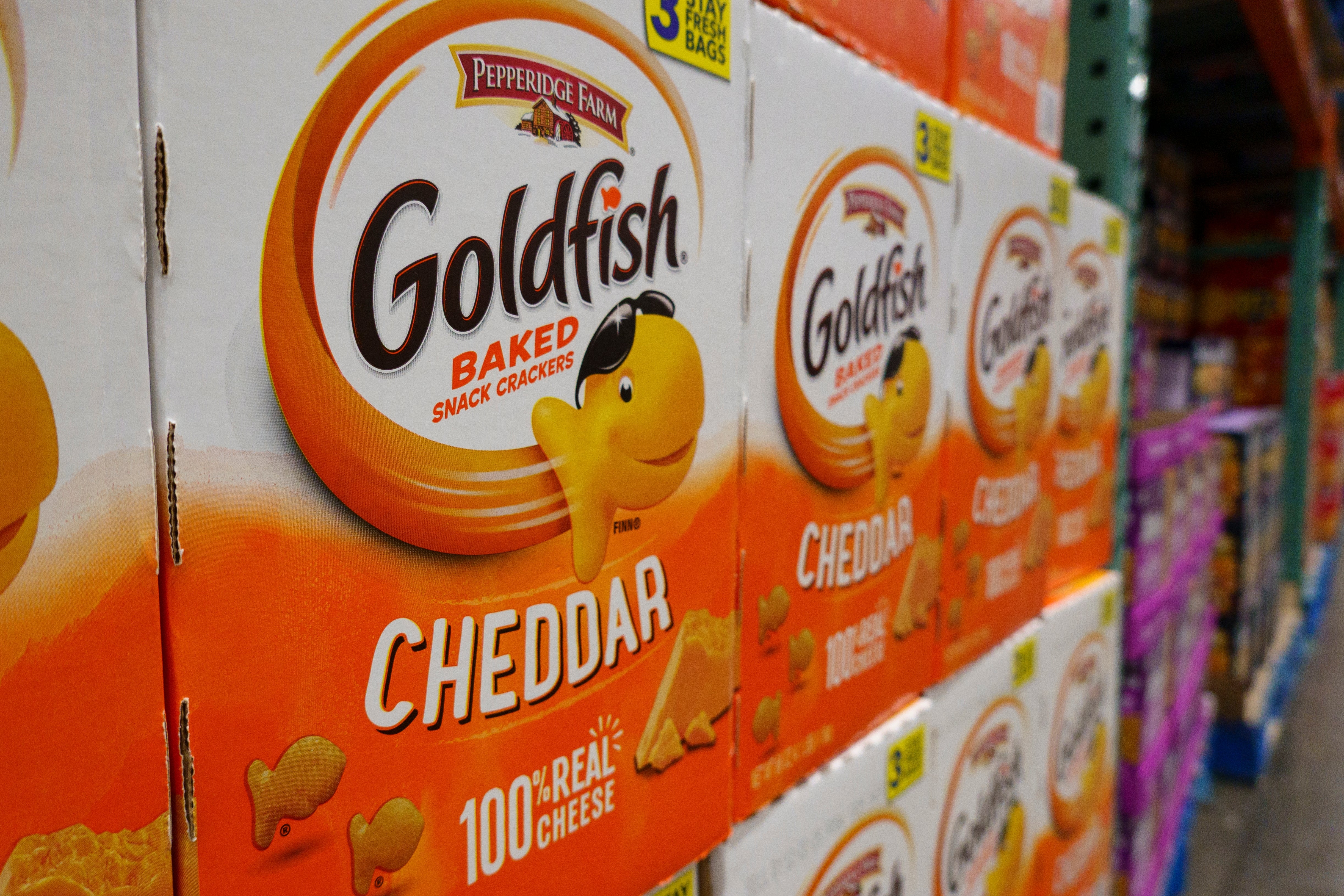 Stacks of Goldfish Cheddar snack boxes are displayed connected a store shelf