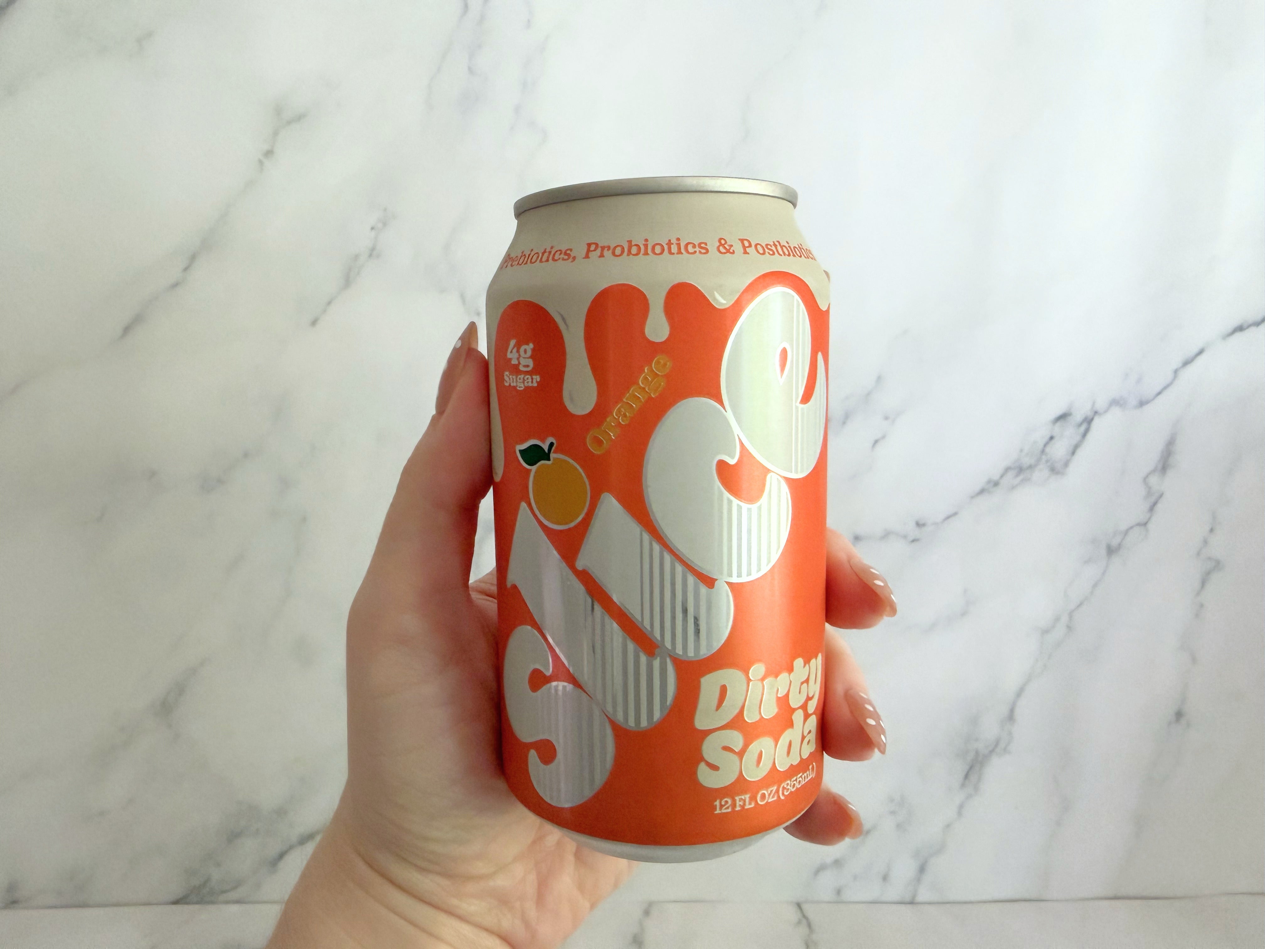 Person holding a can of Slice Dirty Soda, orange flavor, with "4g sugar" label