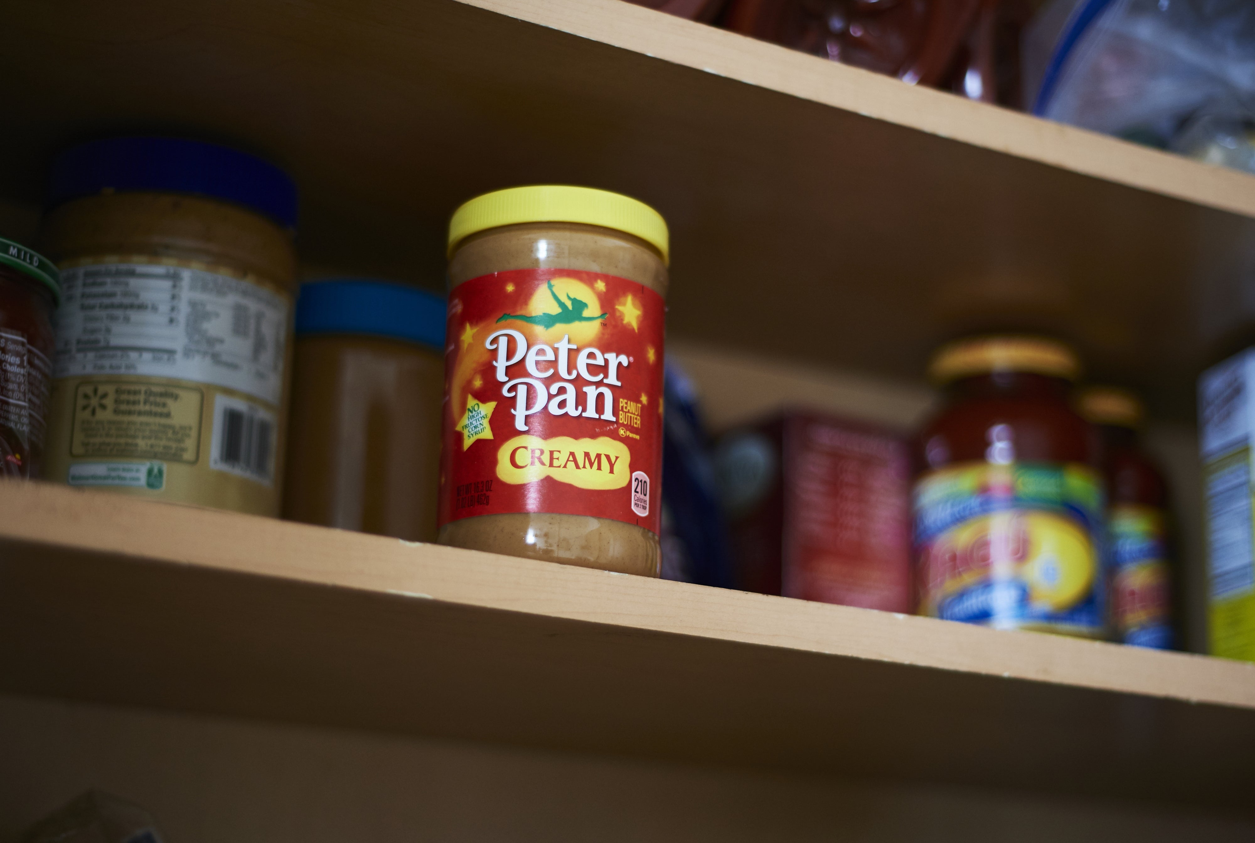 Jar of Peter Pan creamy peanut food connected a pantry support with different nutrient items