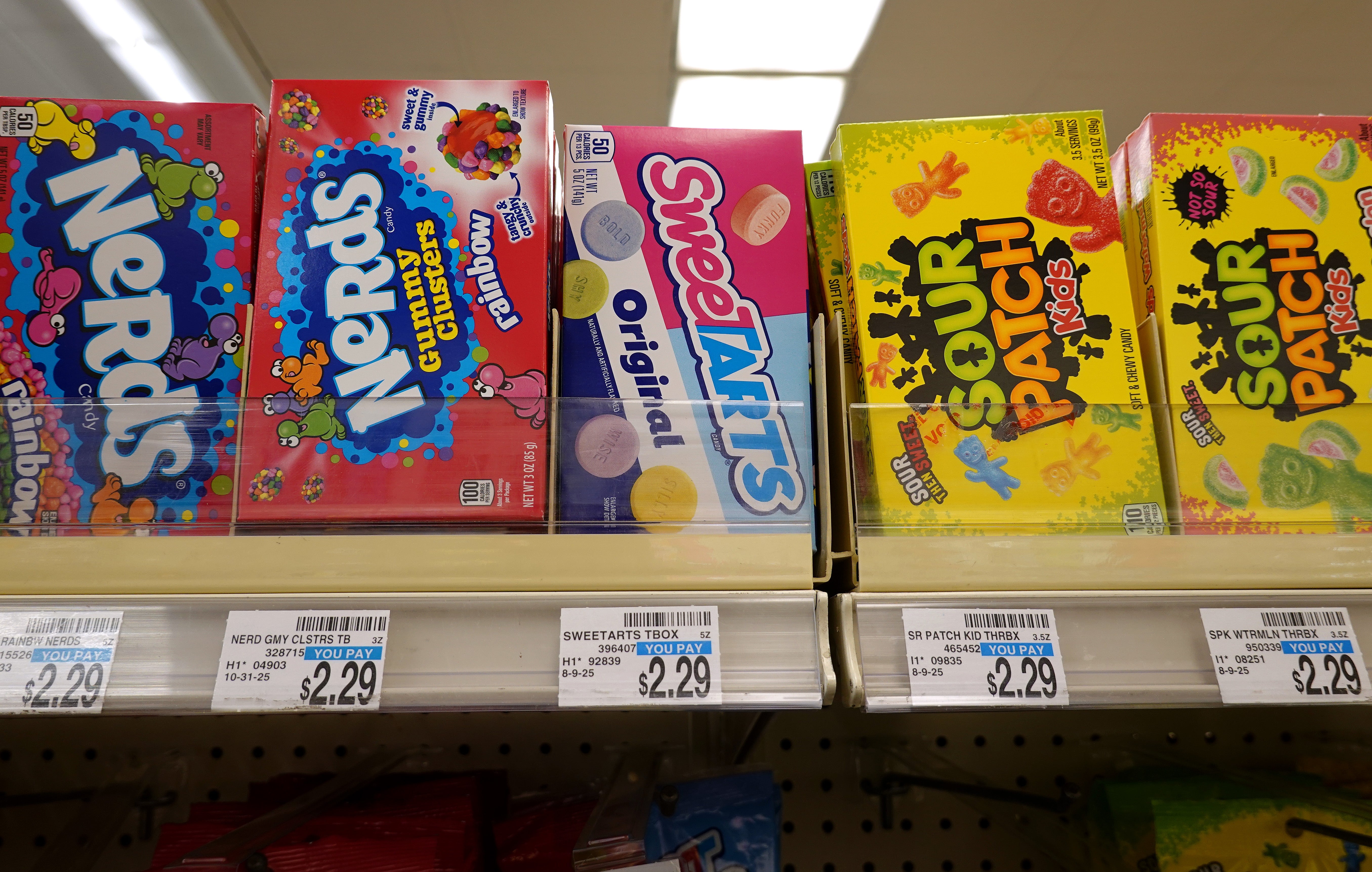 Candy boxes connected a store shelf, including Nerds, Sweetarts, and Sour Patch Kids. Price tags disposable beneath the boxes