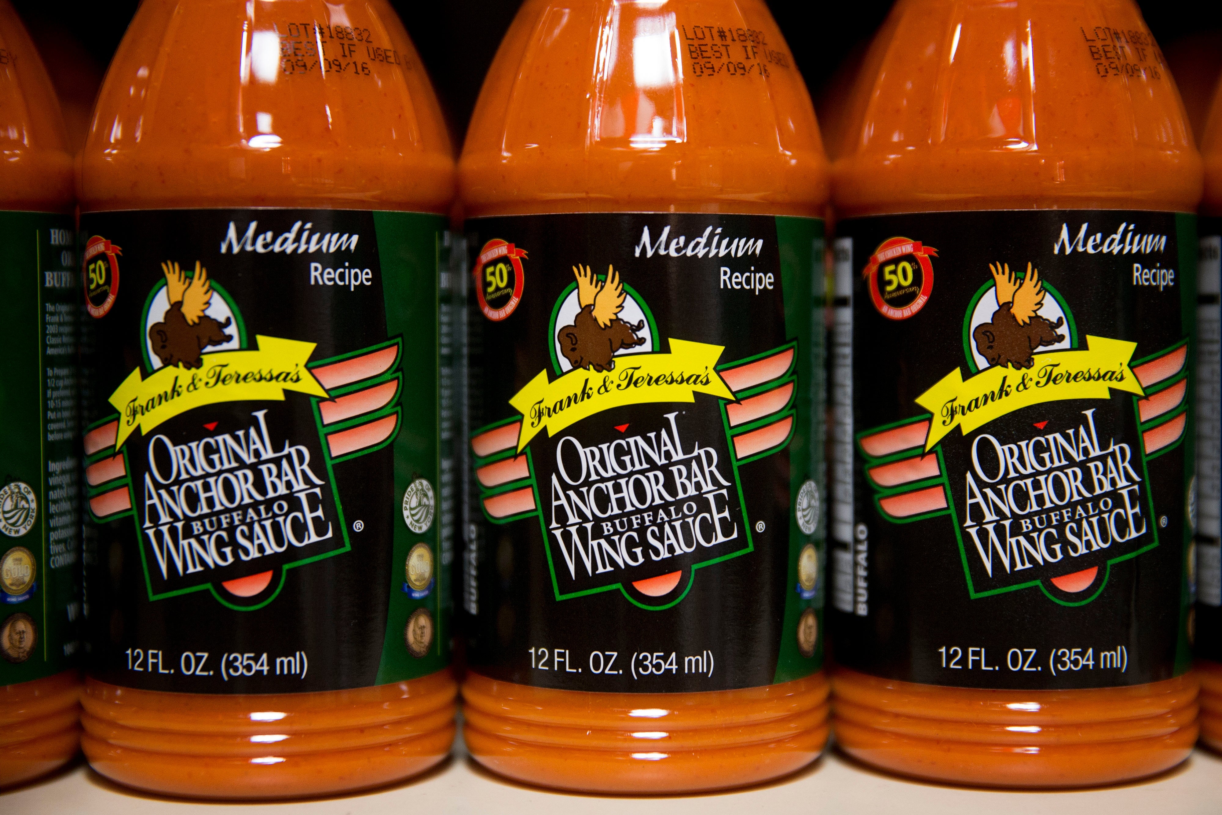 Buffalo helping condiment bottles connected a shelf, labeled "Original Anchor Bar Buffalo Wing Sauce" with mean recipe, successful an nonfiction connected culinary travel