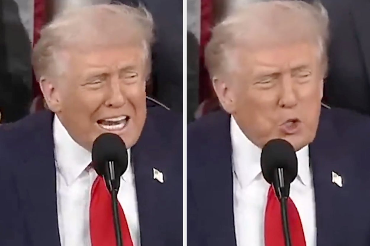 A person in a suit and red tie speaking at a microphone, appearing animated during a public event