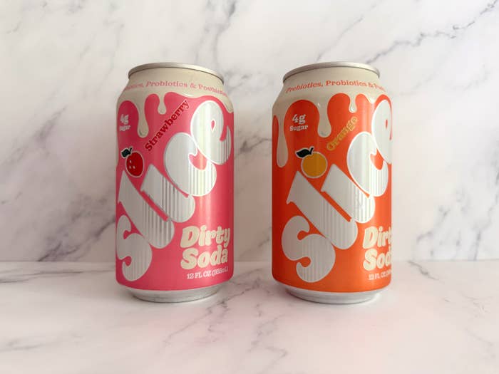 Two cans of Slice Dirty Soda: Strawberry on left and Orange on right, with probiotic and low-sugar labels