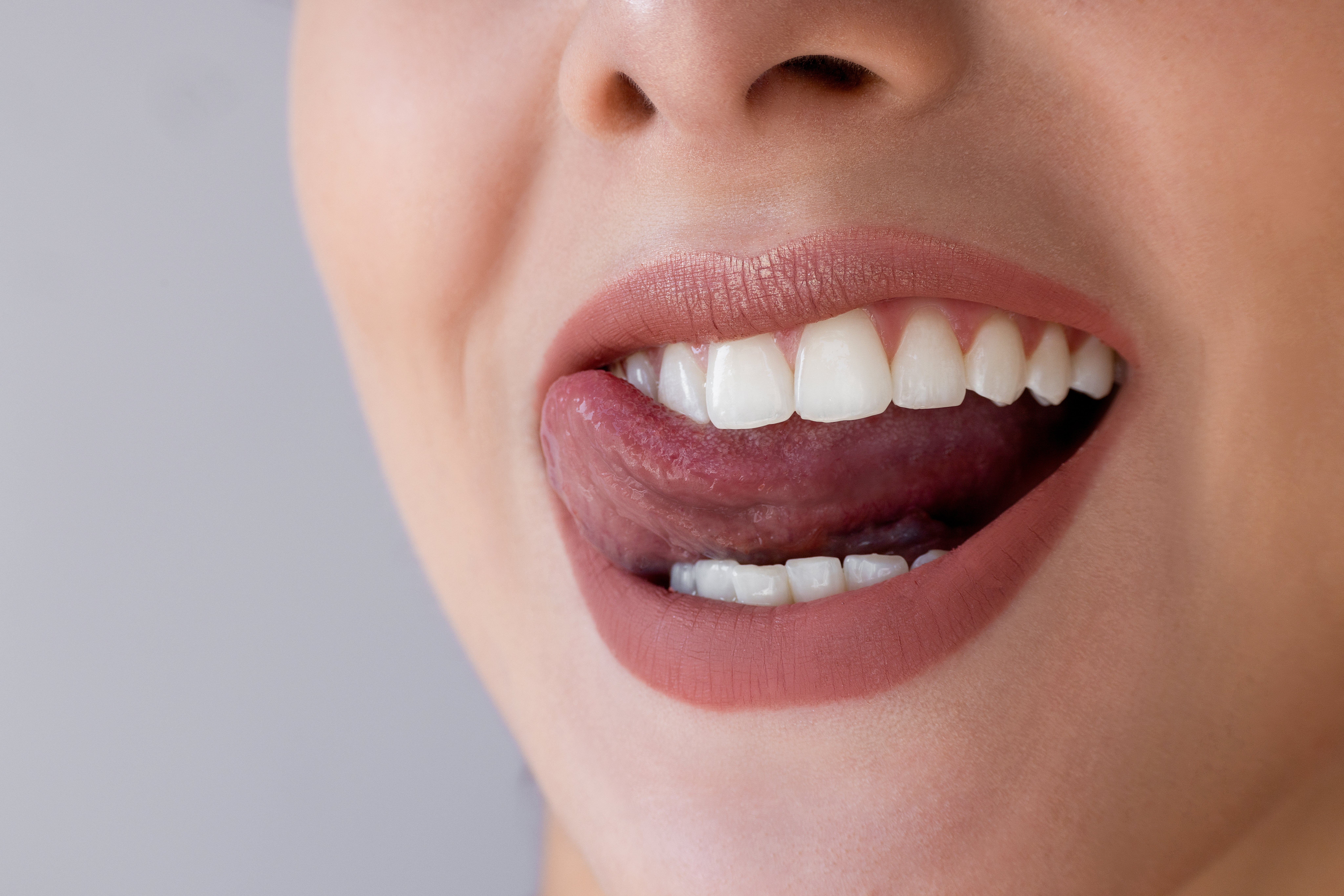 Close-up of a person's rima  arsenic  they playfully lick their precocious    teeth with their tongue, smiling gently