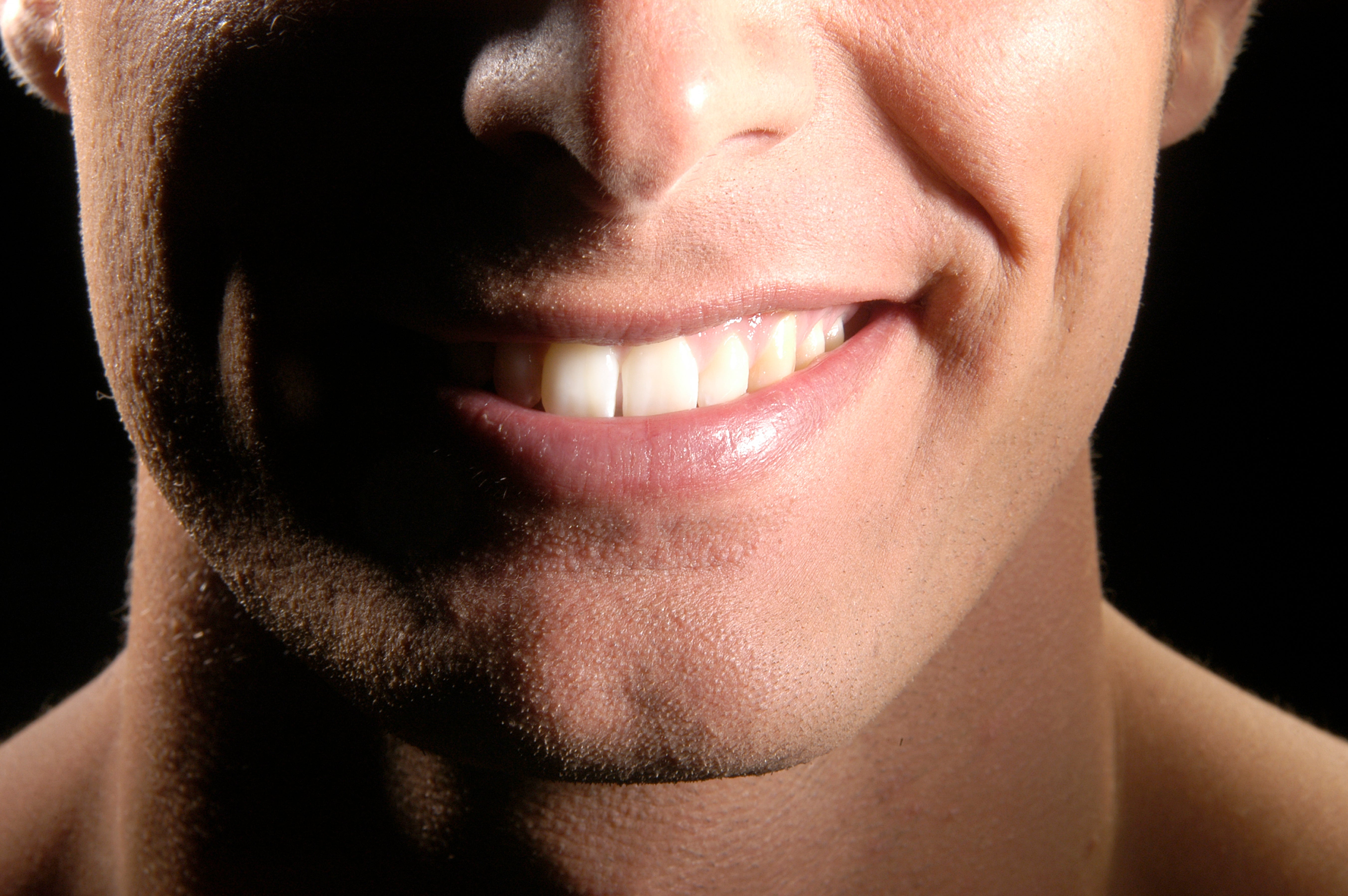 Close-up of a idiosyncratic   smiling, showing their teeth and dimples, against a acheronian  background