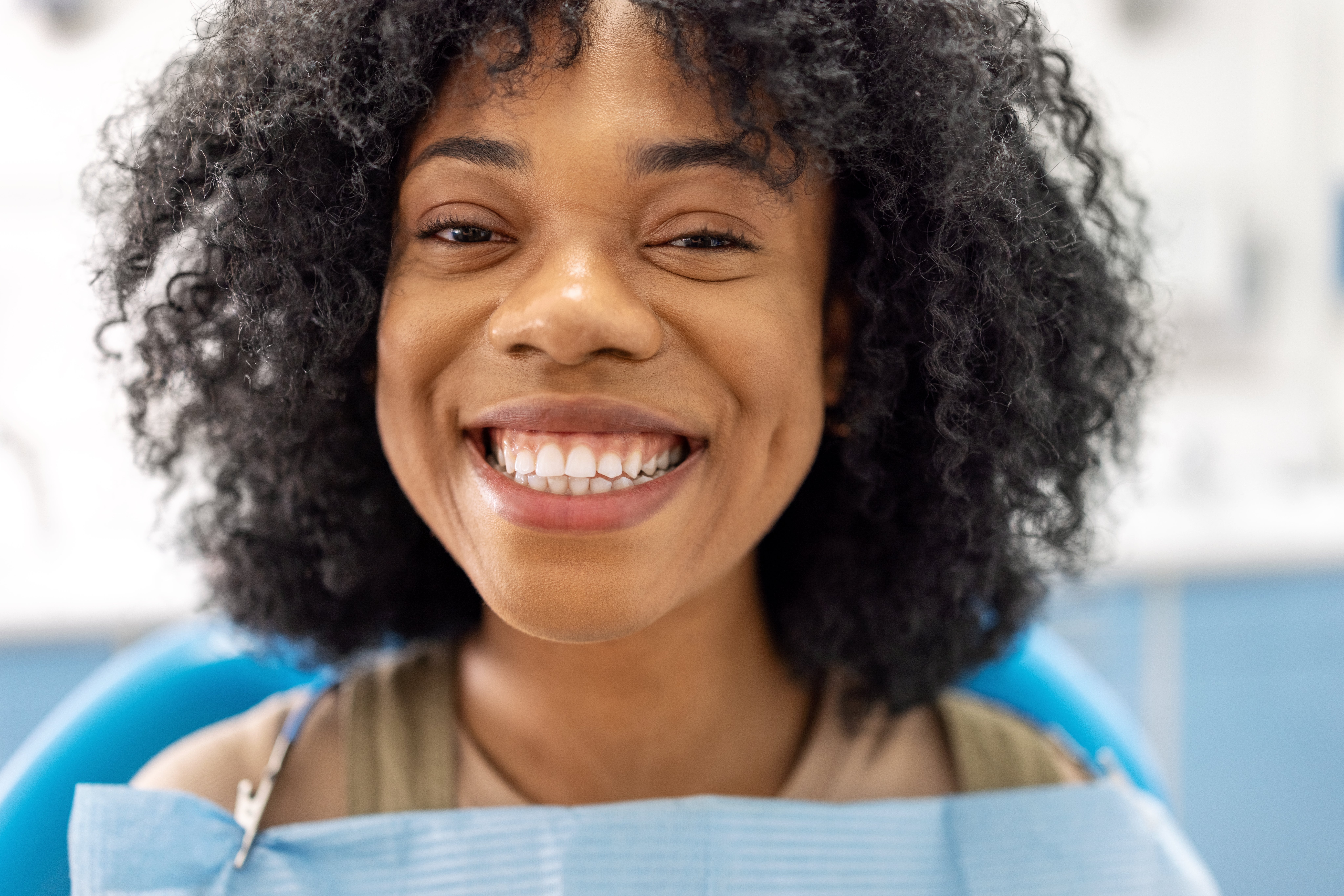 Person smiling portion    seated successful  a dental chair, wearing a dental bib, showcasing a bright, affable  expression