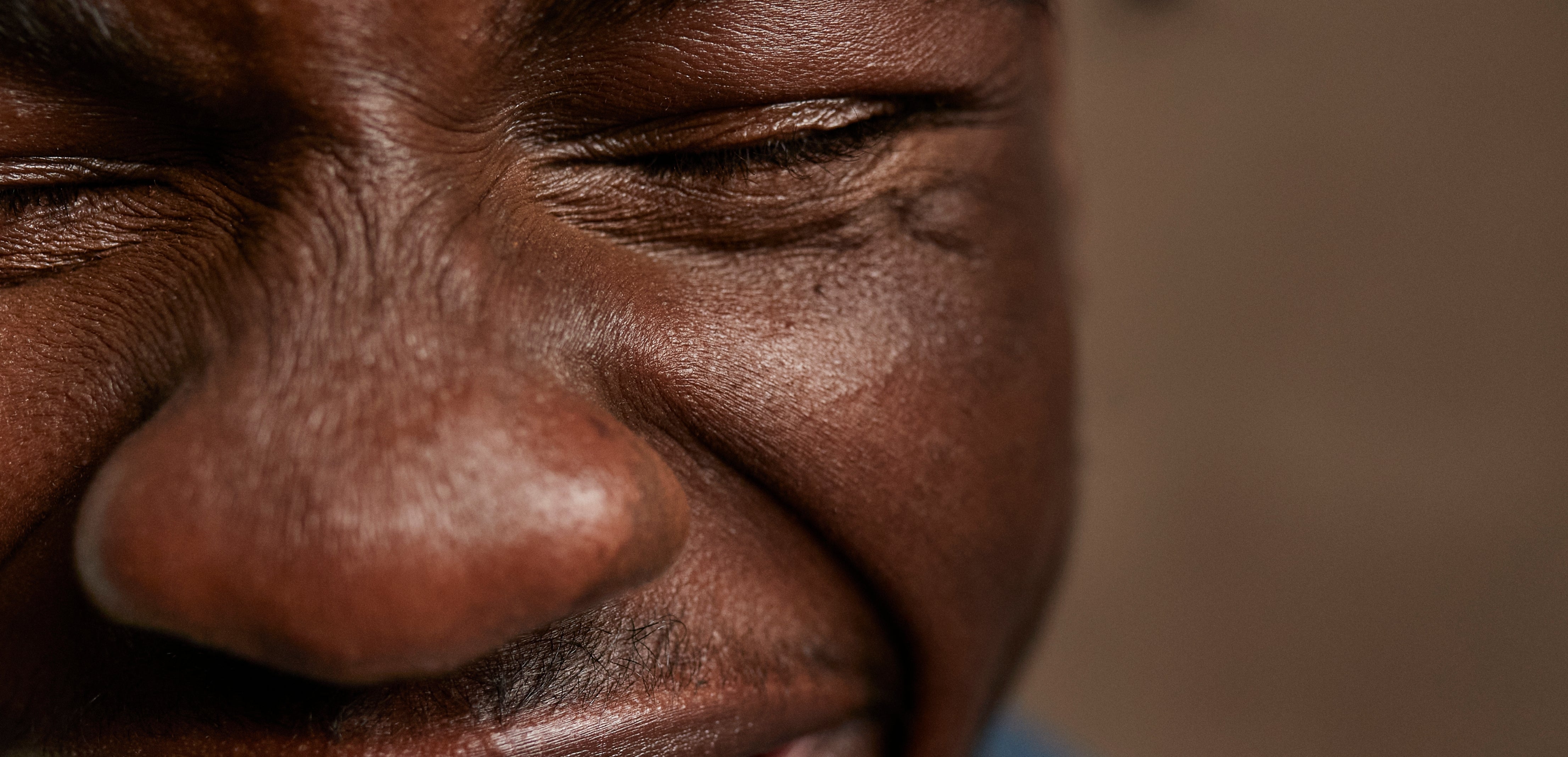 Person smiling with eyes closed, showing joyousness  and happiness. Close-up of look   and teeth visible