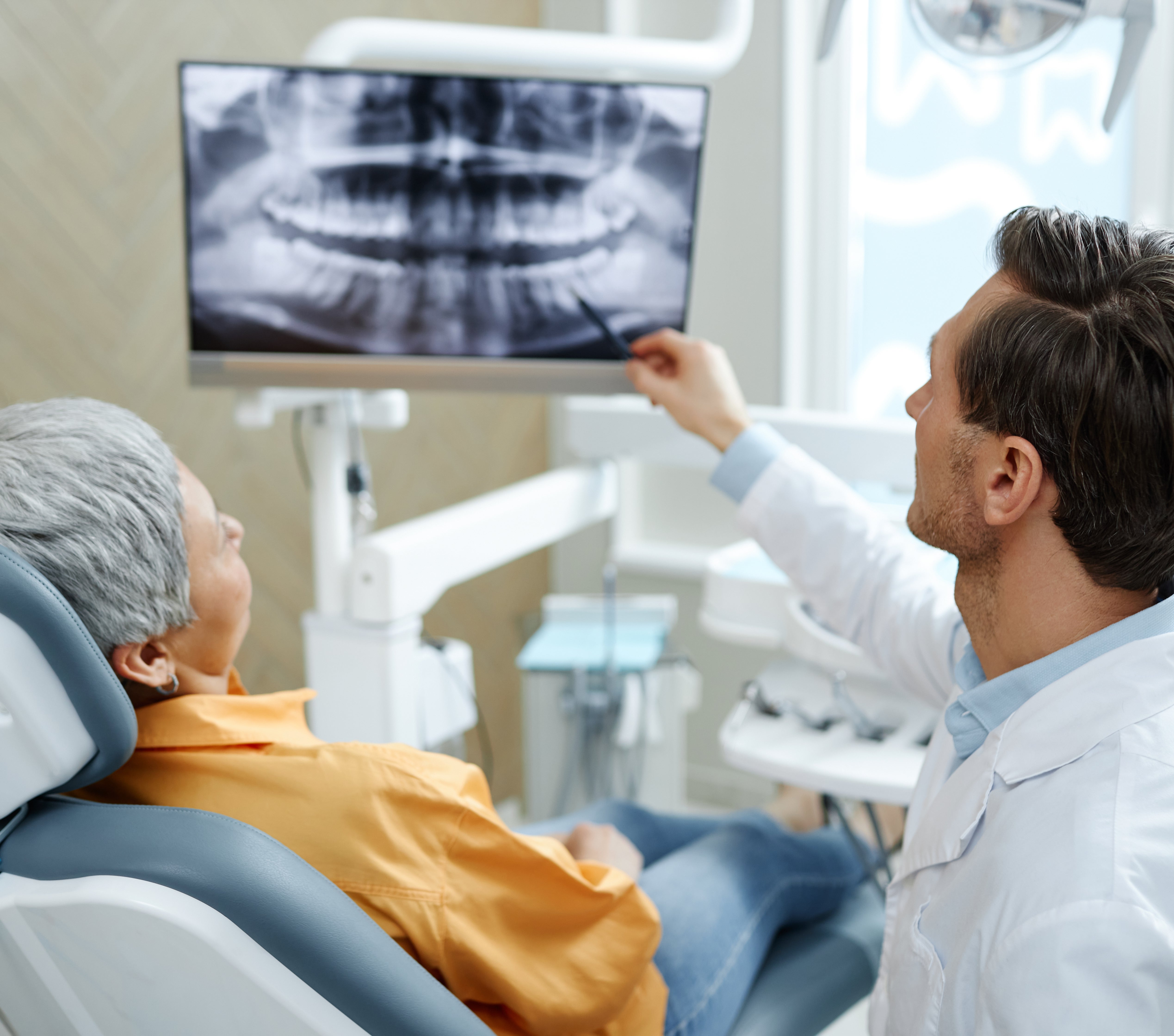 Dentist showing an X-ray to a diligent  reclining successful  a dental chair