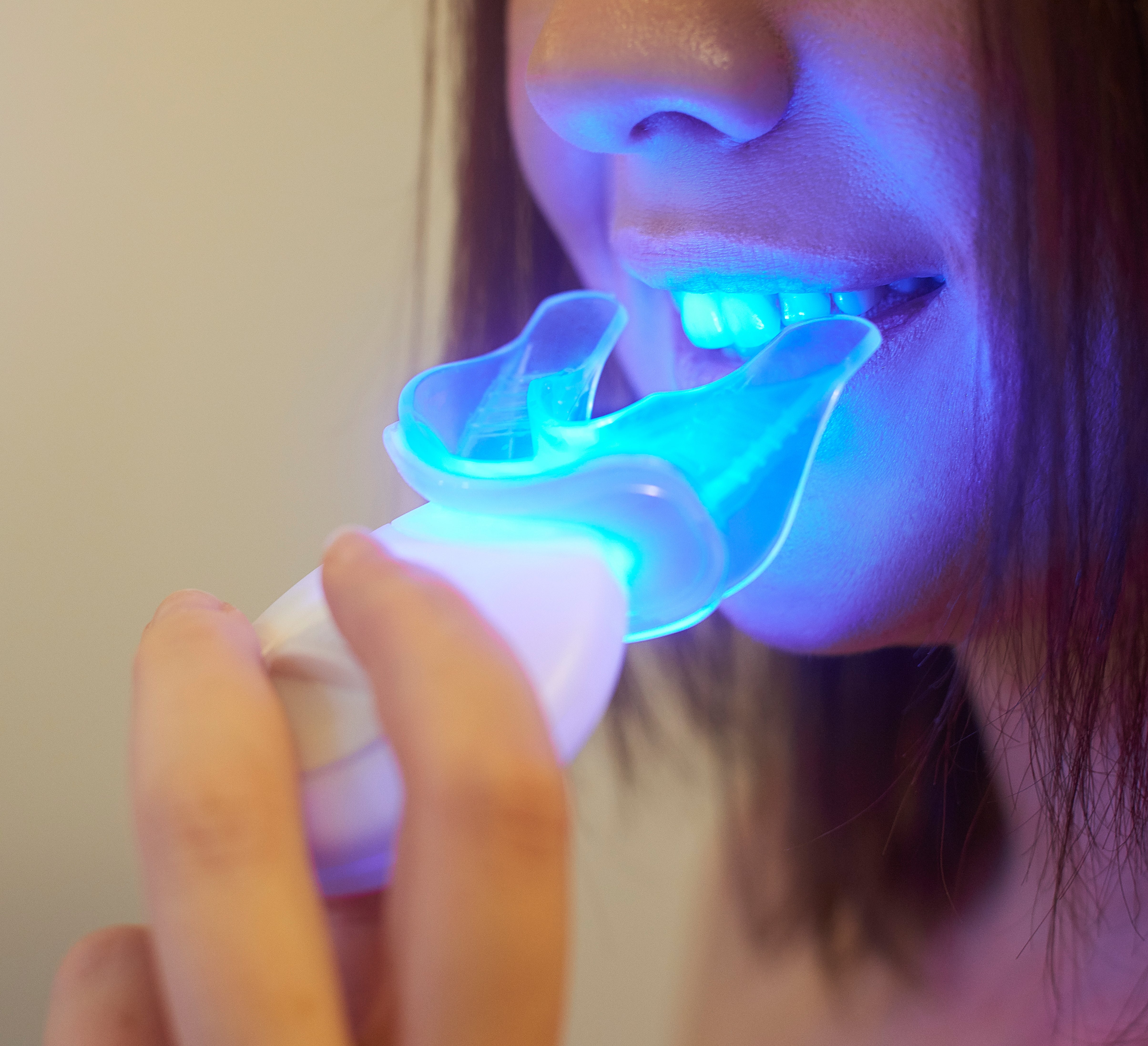 Person utilizing a glowing teeth whitening device, holding it successful  spot  portion    smiling
