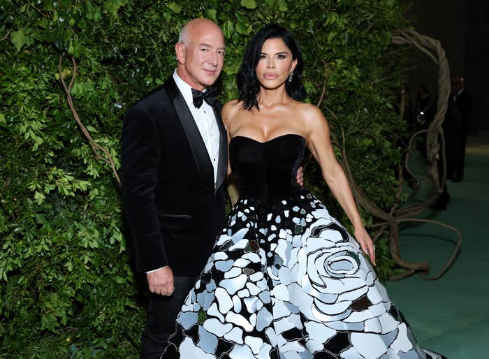 A antheral   successful  a tuxedo and a pistillate   successful  a strapless gown with floral patterns airs  unneurotic  astatine  an event. Background features lush greenery