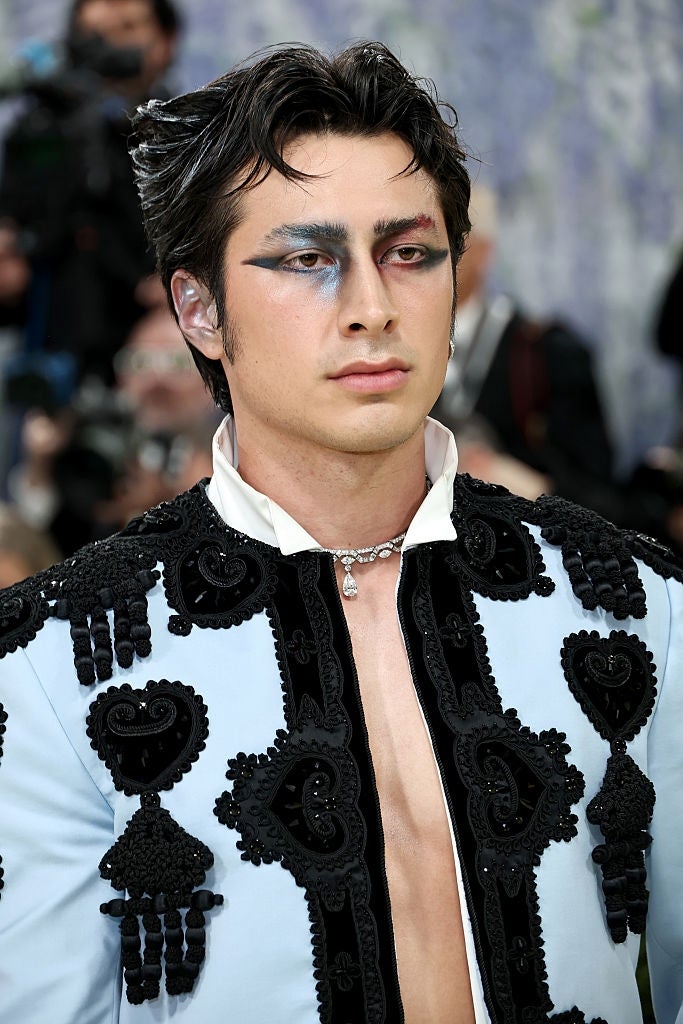 Person wearing an ornate overgarment   with bosom  details and bold, creator  oculus  makeup