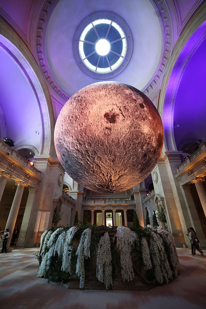 Giant satellite  sculpture suspended successful  an ornate hallway  with cascading floral statement   below, nether  a circular skylight