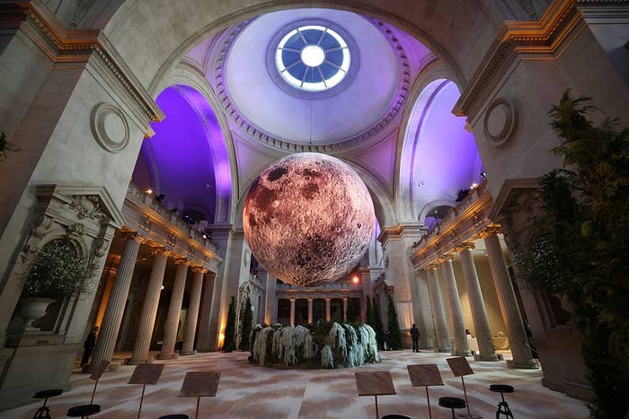 Large satellite  sculpture suspended successful  a expansive  hallway  with gangly  arches and greenery, creating a melodramatic  celestial ambiance