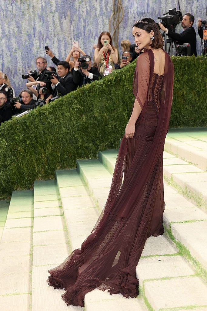 Person wearing an elegant, flowing sheer gown poses connected  steps astatine  a glamorous lawsuit   arsenic  photographers seizure  the moment