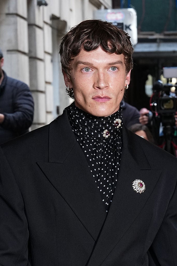 Person successful  a polka dot scarf and achromatic  blazer with a connection    brooch connected  the lapel, looking ahead