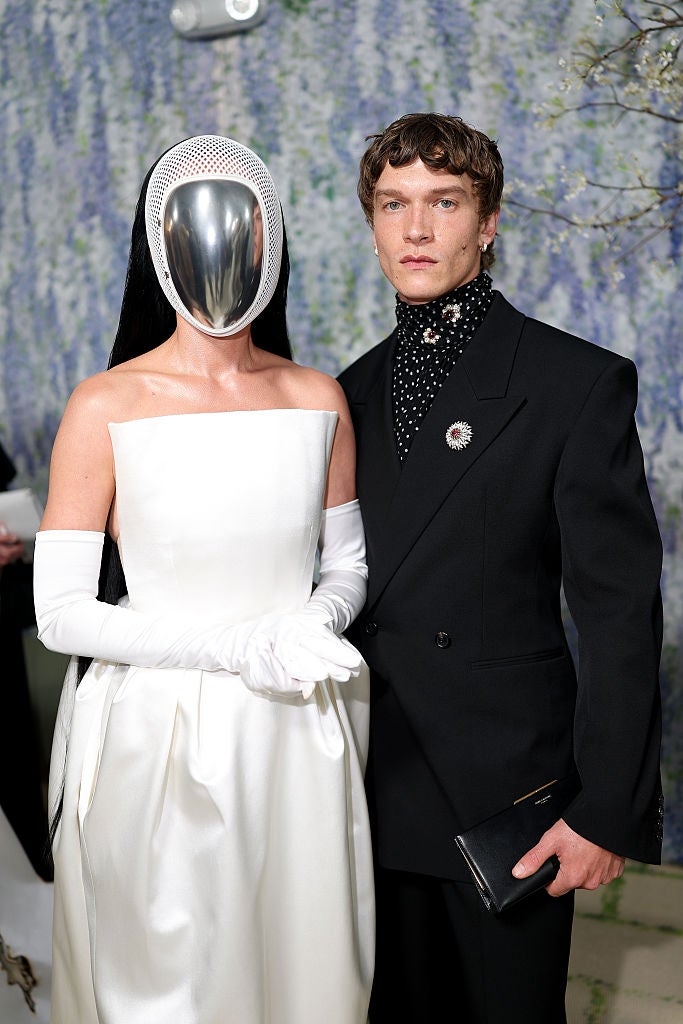 Person with look   disguise  successful  sleek achromatic  formal  and gloves, stands adjacent  to idiosyncratic  successful  achromatic  suit   with pearl-studded turtleneck connected  stylish lawsuit   backdrop