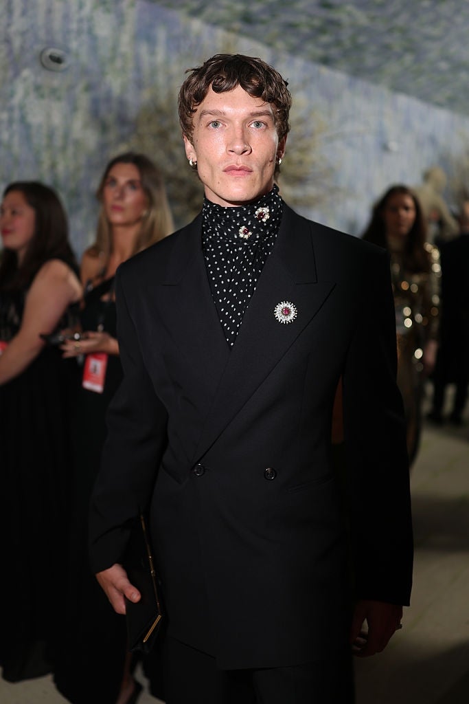 Person successful  elegant double-breasted suit   with polka dot garment  astatine  an event, surrounded by attendees successful  ceremonial  attire