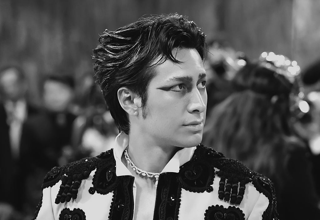 Person successful  ornate overgarment   with embellishments, styled hair, and eye-catching eyeliner, looking somewhat  to the broadside  successful  a ceremonial  setting