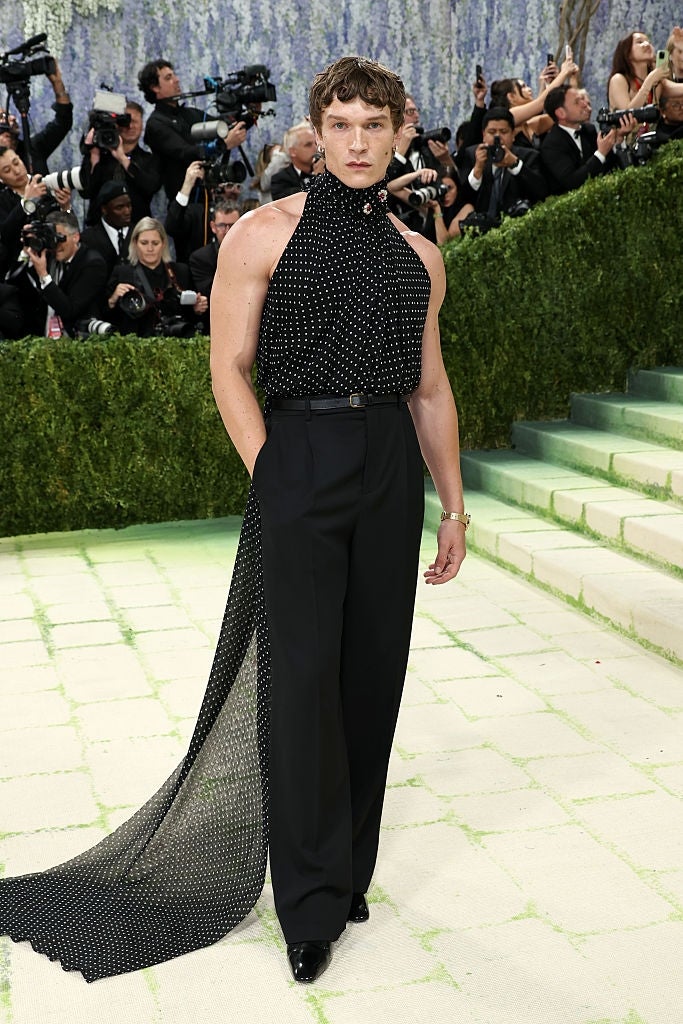 Person connected  reddish  carpet successful  sleeveless, high-neck polka dot apical  with agelong  train, wide-leg pants. Photographers successful  background