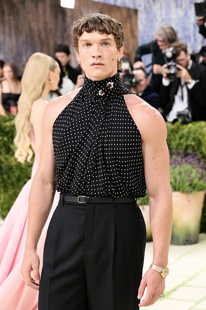 Person successful  a sleeveless, polka dot halter apical  connected  the reddish  carpet, posing confidently