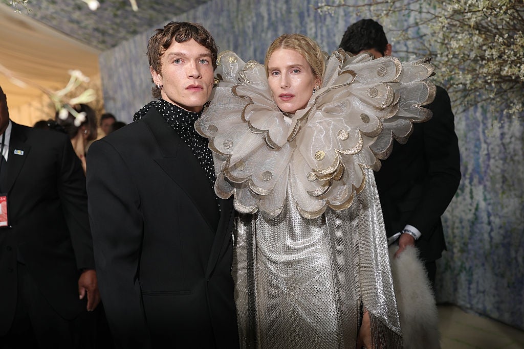 Two individuals basal   connected  the reddish  carpet. One wears a polka-dot suit, the different   a melodramatic  ruffled cape and metallic  gown