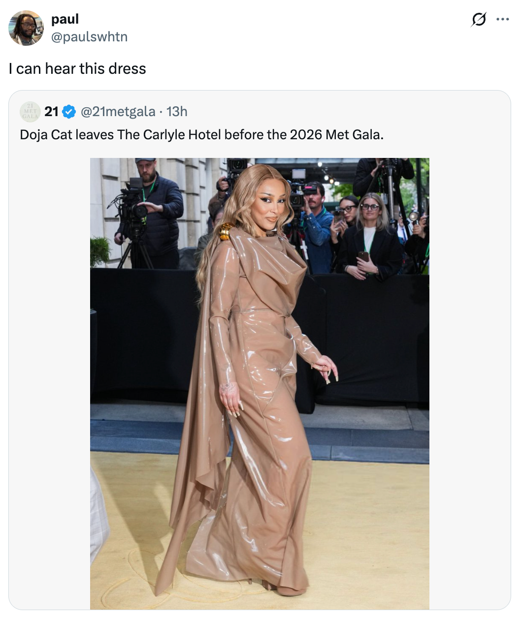 Doja Cat dalam gaun krem ​​​​futuristik dengan tudung panjang, berpose di atas karpet, ditangkap oleh fotografer sebelum Met Gala 2026