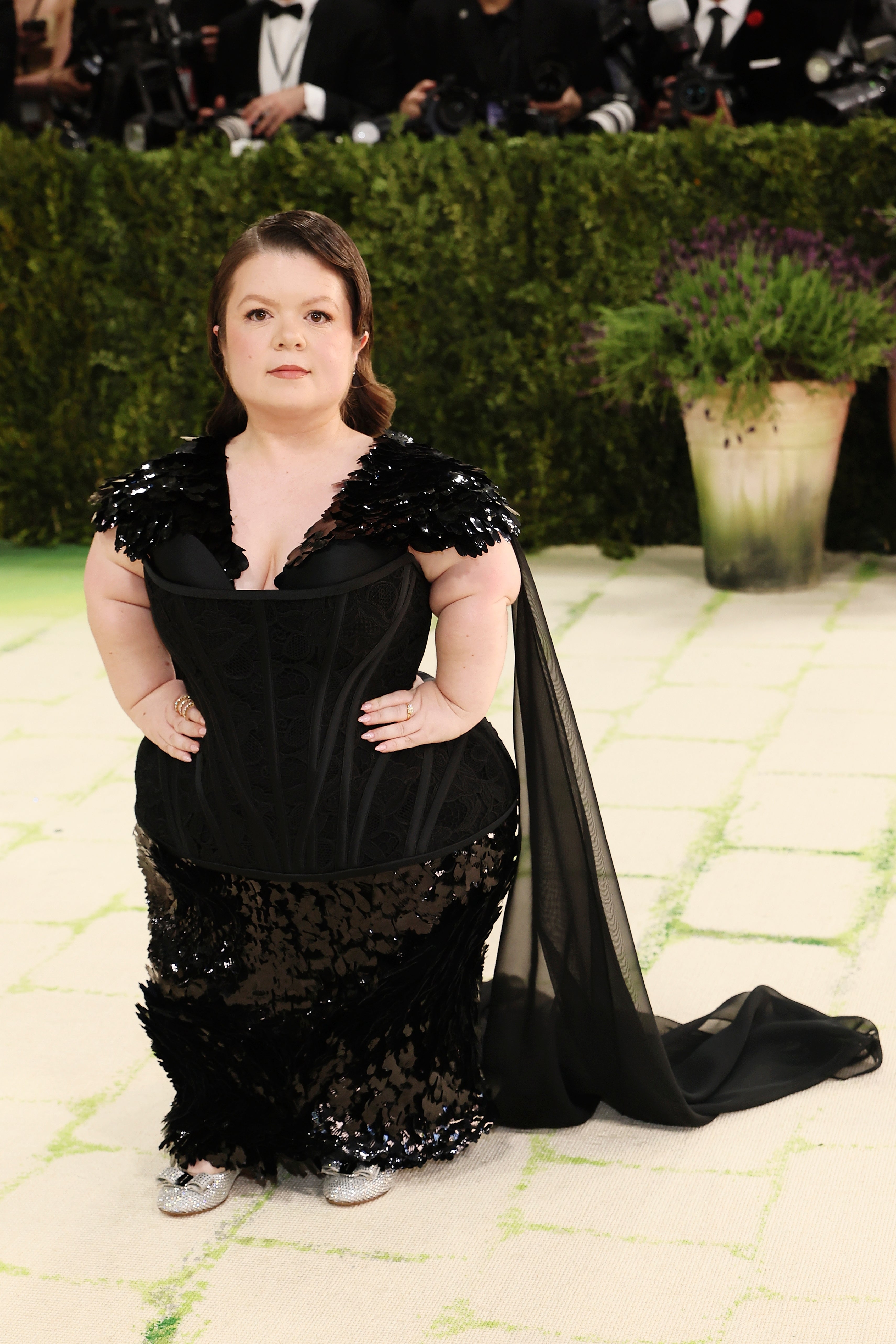 Person successful  a achromatic  sequined gown with a agelong  train, lasting  connected  a carpeted lawsuit   with photographers successful  the background