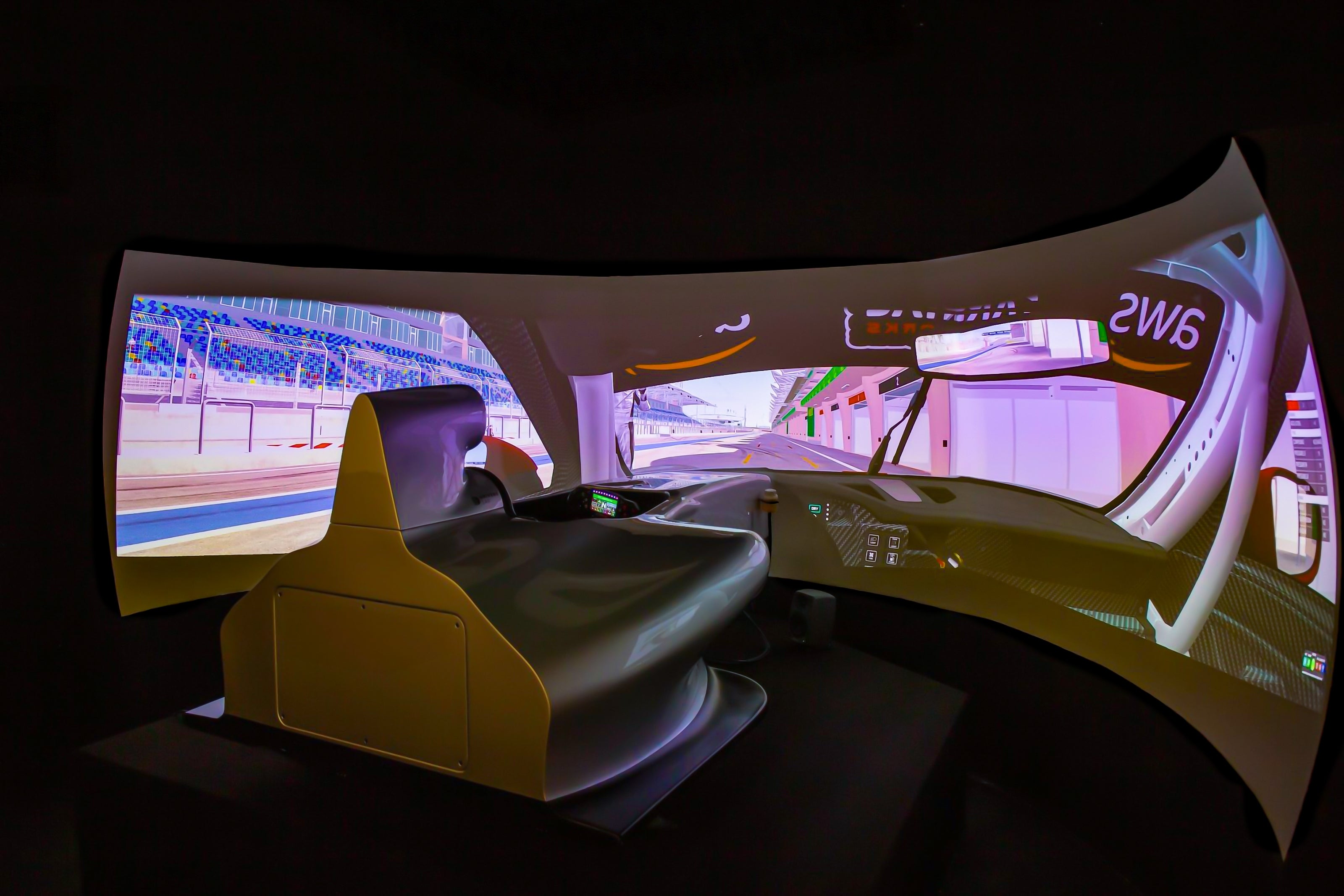 Driving simulator with a curved screen displaying a racetrack view, providing an immersive experience for users in a seat resembling a car cockpit