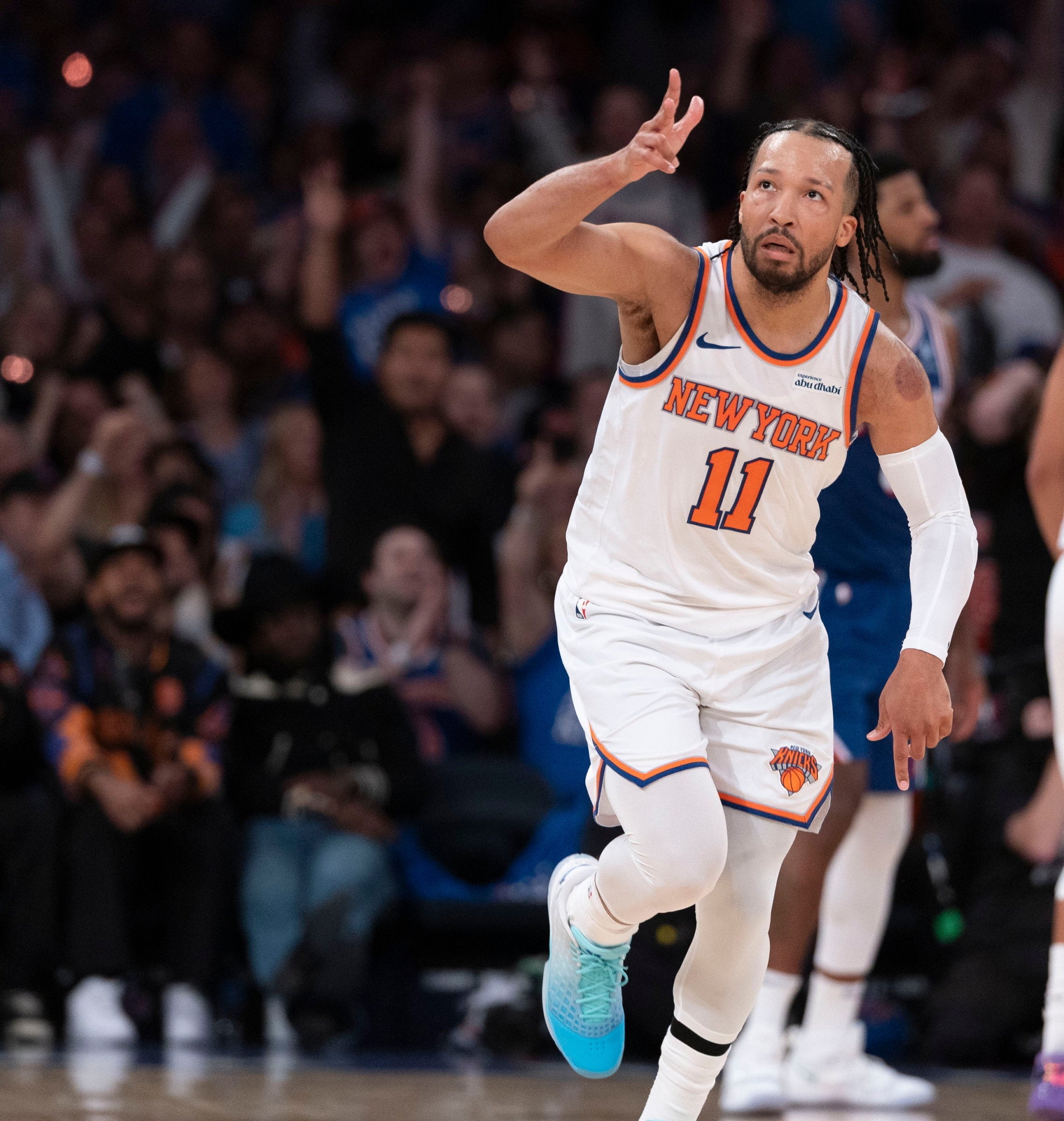 Basketball player, wearing a Knicks jersey, gestures mid-game connected  a engaged  tribunal  with an assemblage  successful  the background