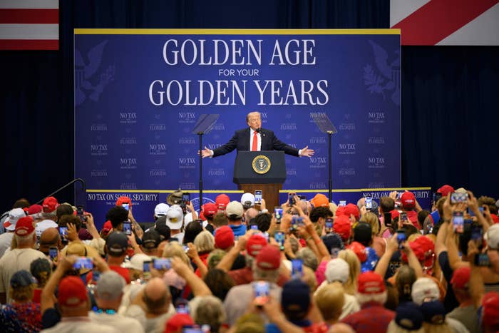 A fig  connected  signifier    astatine  a podium during a nationalist   event, surrounded by a ample  assemblage  wearing hats. The backdrop reads "Golden Age for Your Golden Years."