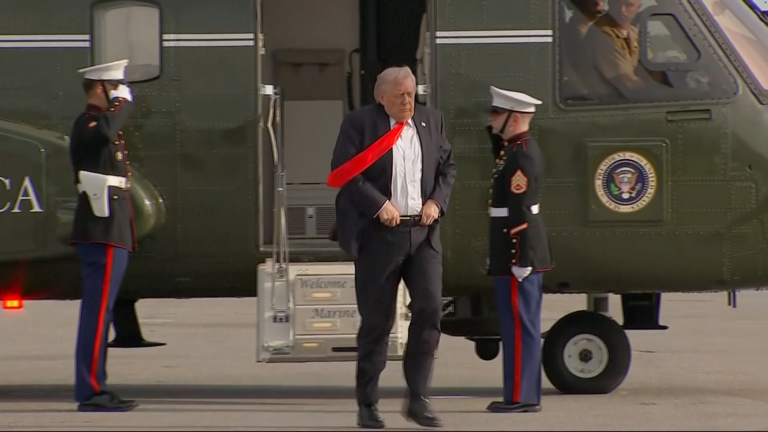 A idiosyncratic   exits a helicopter, flanked by 2  saluting Marines