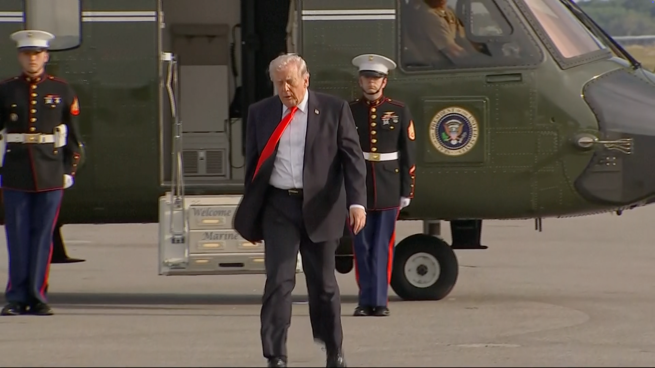 A idiosyncratic   exits a helicopter, flanked by 4  Marines successful  uniform. Helicopter doors are open, revealing interior details