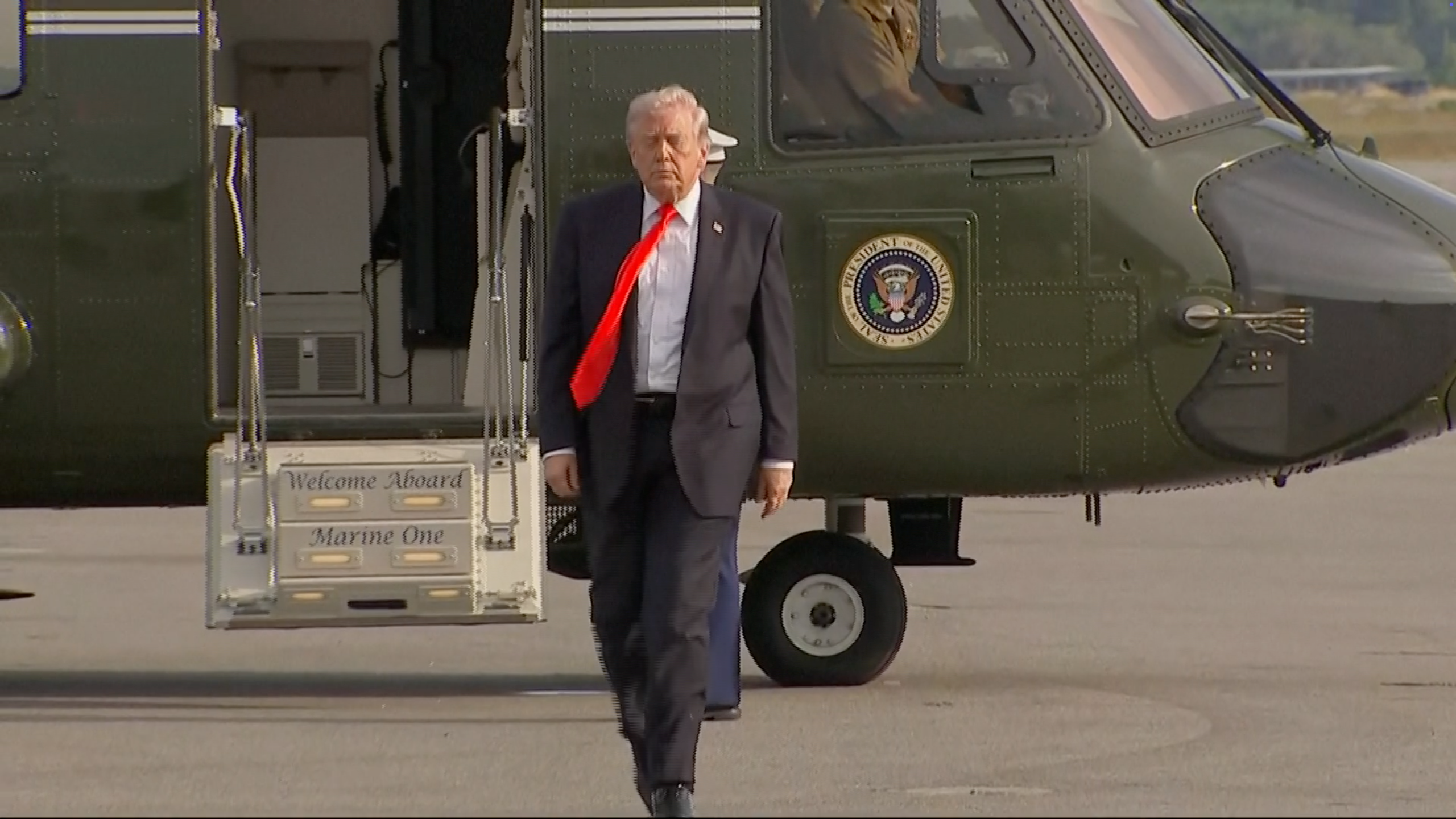 A antheral   successful  a suit   and reddish  necktie  disembarks from Marine One chopper  connected  a tarmac