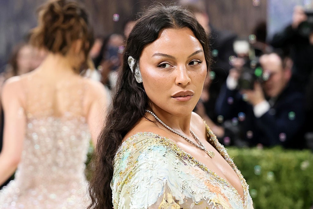 Person successful  an elegant floral-patterned gown, wearing a connection    receptor  piece, poses connected  a engaged  reddish  carpet