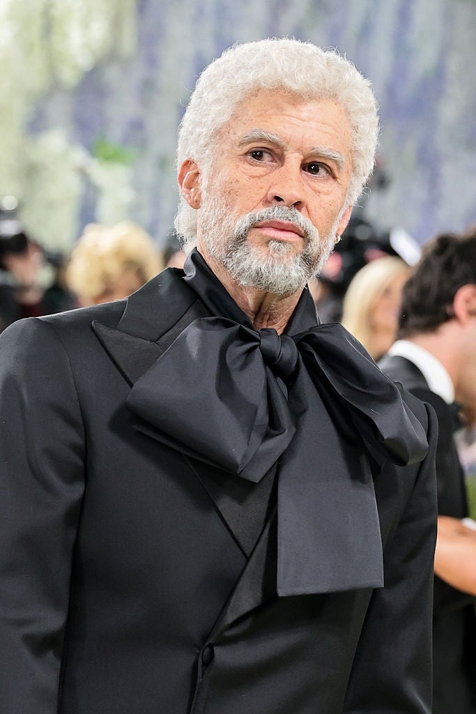 Individual successful  ceremonial  attire with a ample  collar bow astatine  a high-profile event. Background shows blurred figures