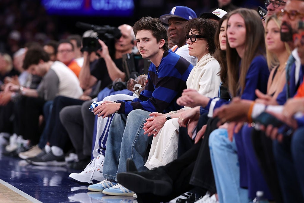 A radical  of radical   beryllium   courtside astatine  a hoops  game, including individuals successful  casual attire and 1  wearing a striped sweater
