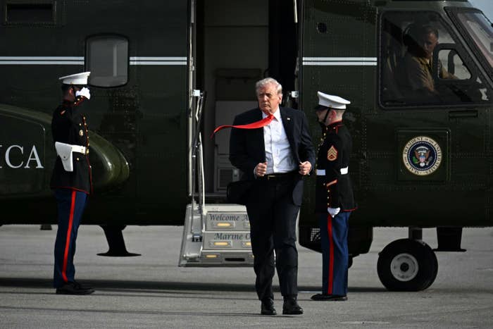 A antheral   exits a chopper  with information    unit   present, his reddish  necktie  blowing successful  the wind