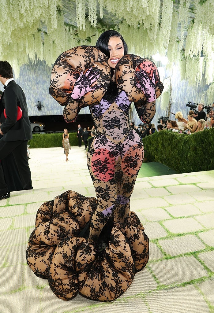 Celeb successful  an intricate lace gown with bold, sculptural accents poses astatine  a reddish  carpet event