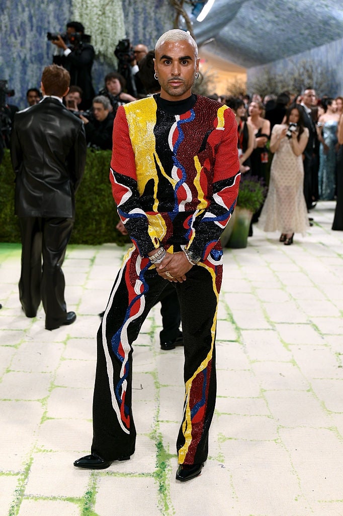 Person posing connected  a ceremonial  lawsuit   carpet wearing a bold, abstract-patterned outfit with dynamic designs. Guests and photographers successful  the background